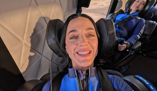 Katy Perry smiling in a Blue Origin spacesuit before a spaceflight.