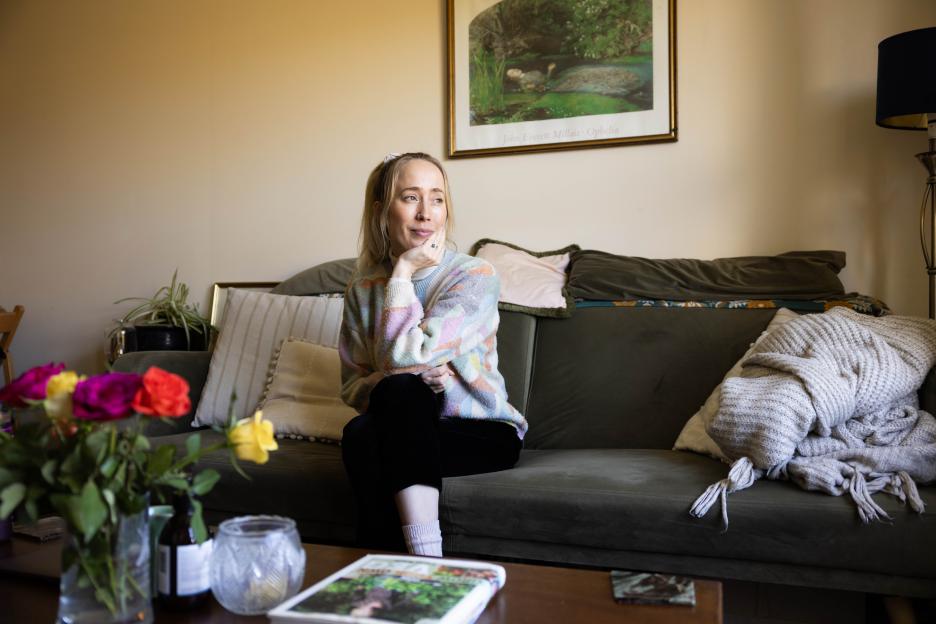 Comedian Kate-Lois Elliott sitting on a couch.