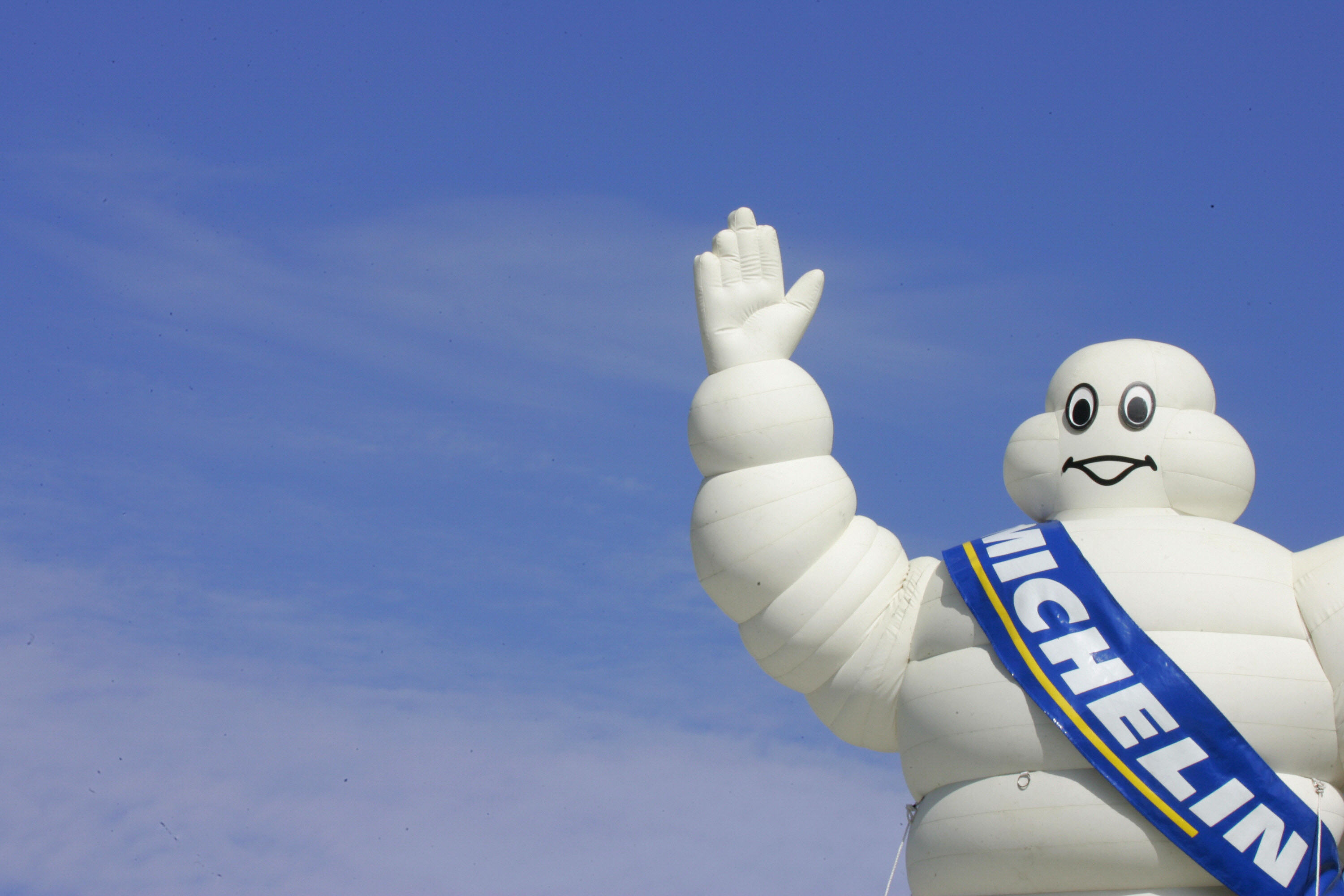 Michelin Man inflatable waving against a blue sky.