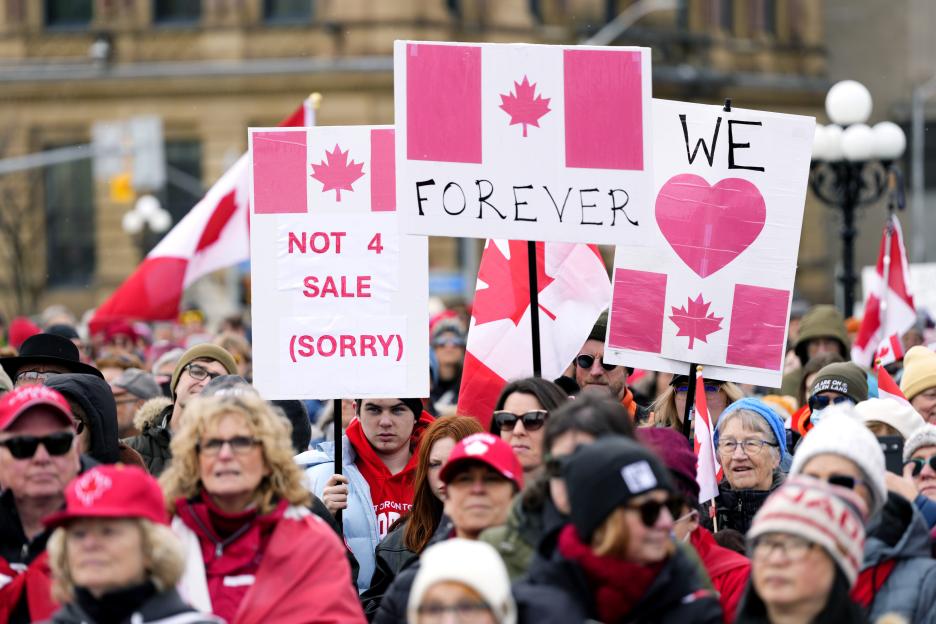 Protestors holding signs that read "Not 4 Sale (Sorry)" and "Forever" at a rally.