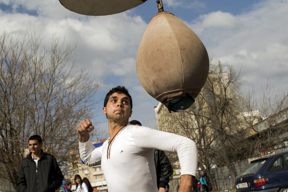 A young man showing his strength by hitting a punching bag at a bride market.