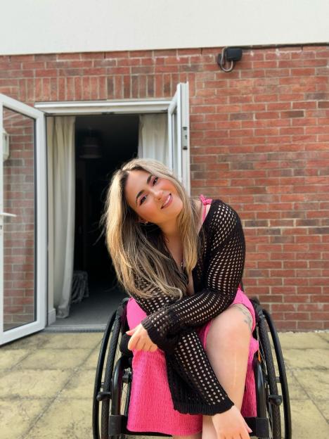 Woman in wheelchair smiling outdoors.