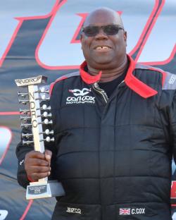 Carl Cox holding a drag racing championship trophy.