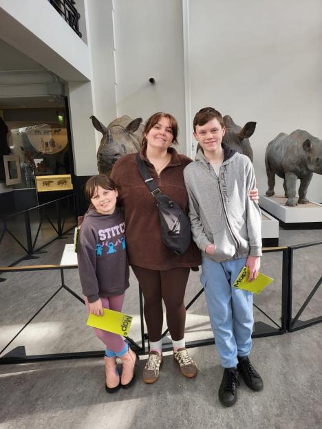 Family posing in front of rhino exhibits at a museum.