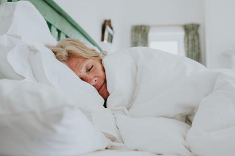 Woman sleeping under a white duvet.