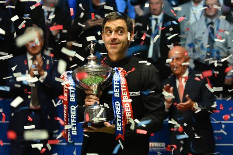 Ronnie O'Sullivan celebrates winning a snooker championship trophy.