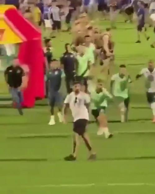 A soccer player kicks a fan on the field.