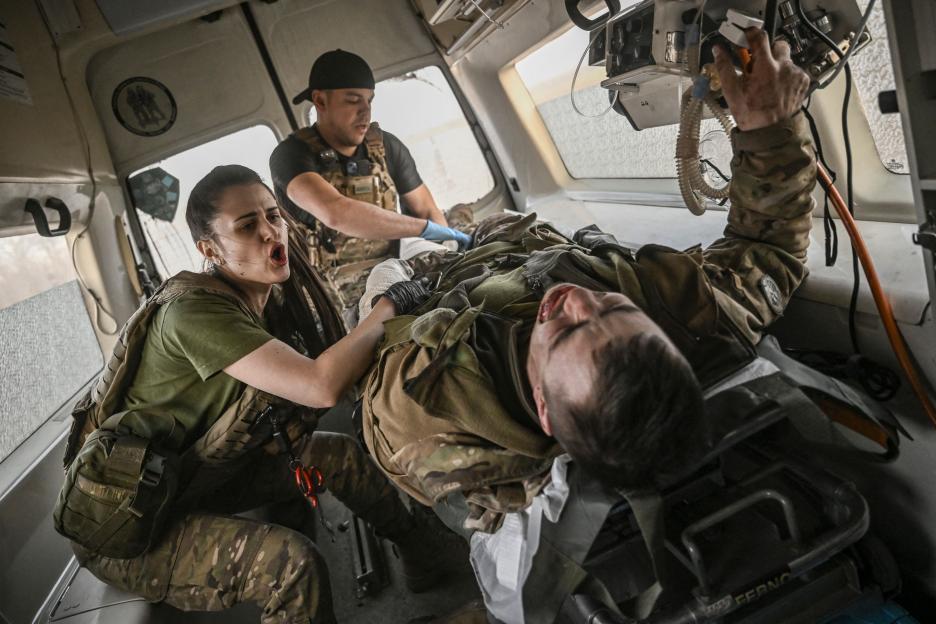 Ukrainian military paramedics treating a wounded soldier in an ambulance.