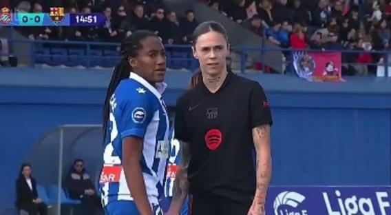 Two female soccer players standing side-by-side on a field.