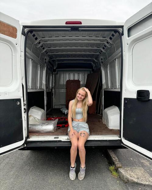 Young woman sitting in the back of a van.