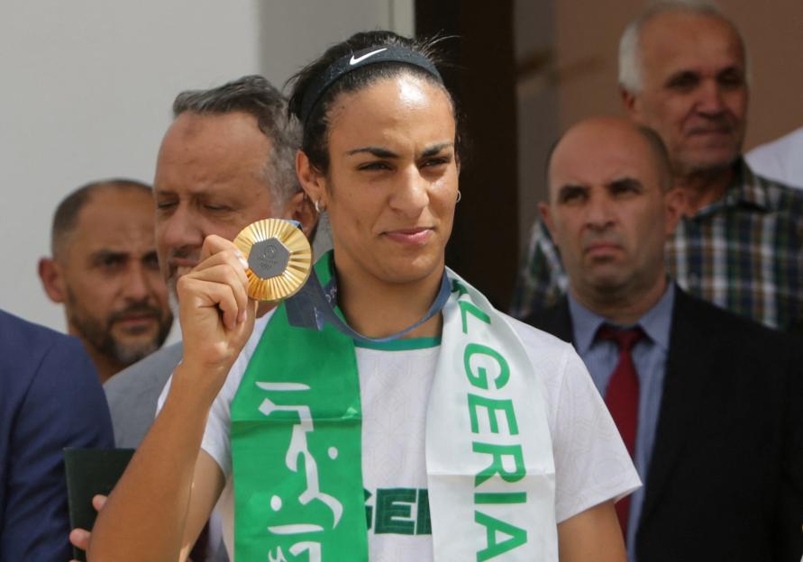 Algerian boxer Imane Khelif holding her gold medal at the airport.