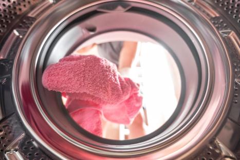 A person's legs and a pink towel seen from inside a washing machine.