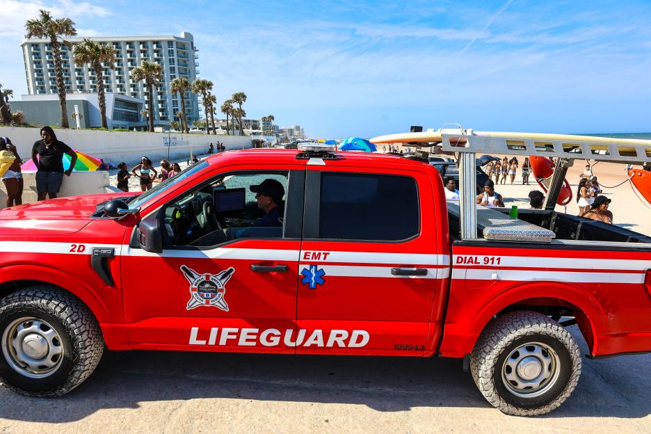 Beach lifeguard truck at a crowded beach.