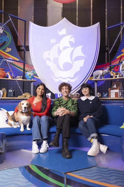 Three Blue Peter presenters and a dog sitting on a couch.