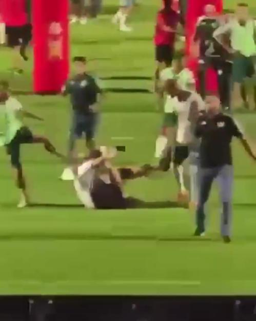 A soccer player kicking a fan on the field.