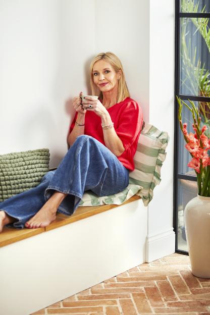 Woman sitting on a window seat holding a mug.