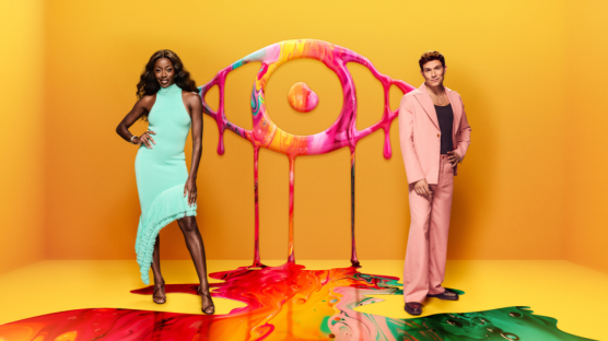 Promotional image for a show featuring two hosts standing on a colorful paint spill, with a large, dripping paint eye behind them.