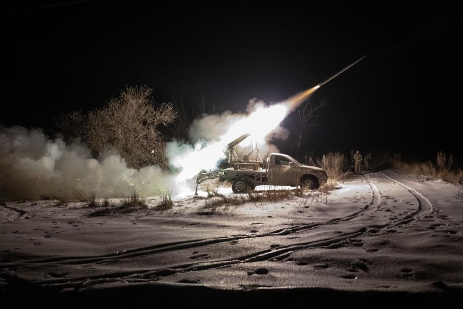 Ukrainian soldiers firing a Mini Grad rocket launcher at night.