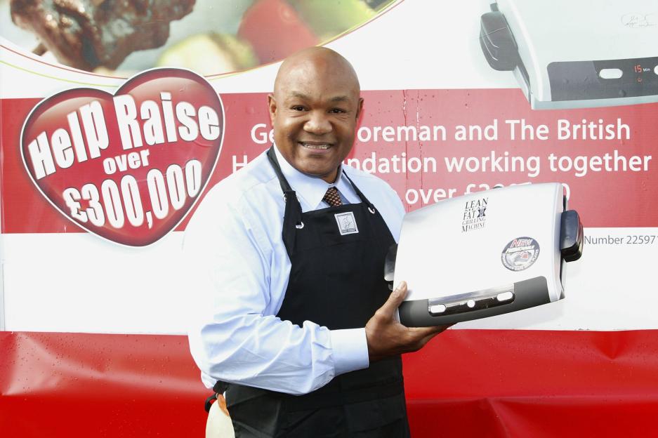 George Foreman holding his grill at a fundraising event.