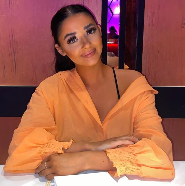 Woman in orange shirt sitting at a table.