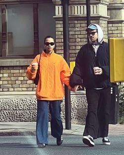 Harry Styles and Taylor Russell holding hands and coffee cups.
