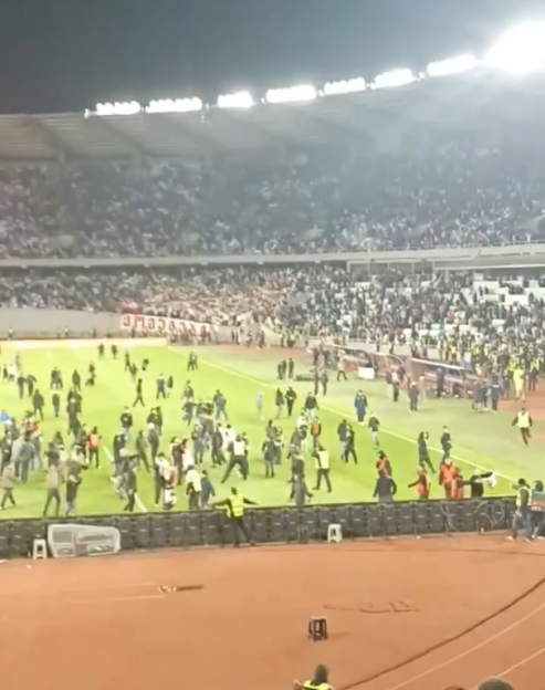 Crowd rushing onto a soccer field.