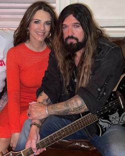 Liz Hurley and Billy Ray Cyrus sitting together.