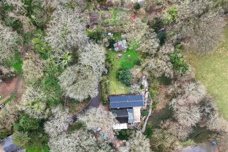 Aerial view of a mobile home in a wooded area.