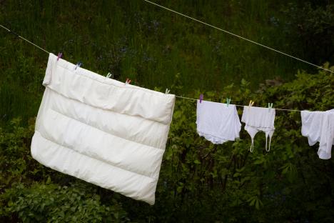 White bedding and clothing hanging on a clothesline outdoors.