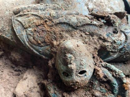 Close-up of a corroded Iron Age mask-like face from the Melsonby hoard.