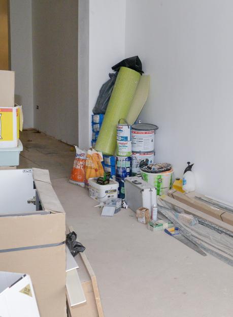 Construction materials and tools piled in a corner of a room.