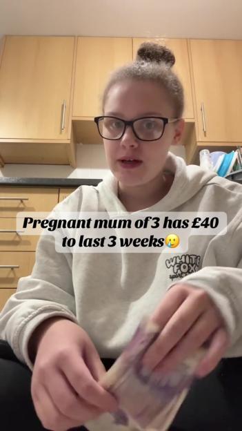 Pregnant mother of three holding £40, stating it's all she has for three weeks.