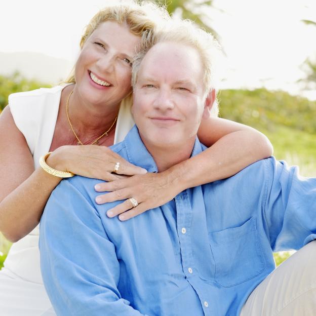 A smiling couple embracing outdoors.