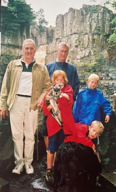 Family photo with two dogs near a waterfall.