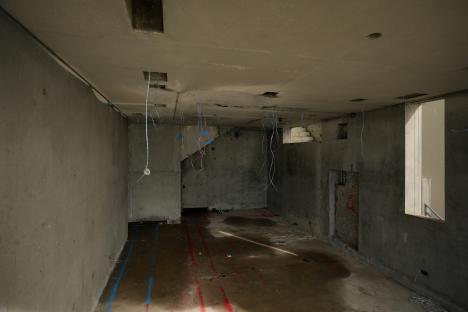 Interior of an unfinished concrete room with exposed wires.