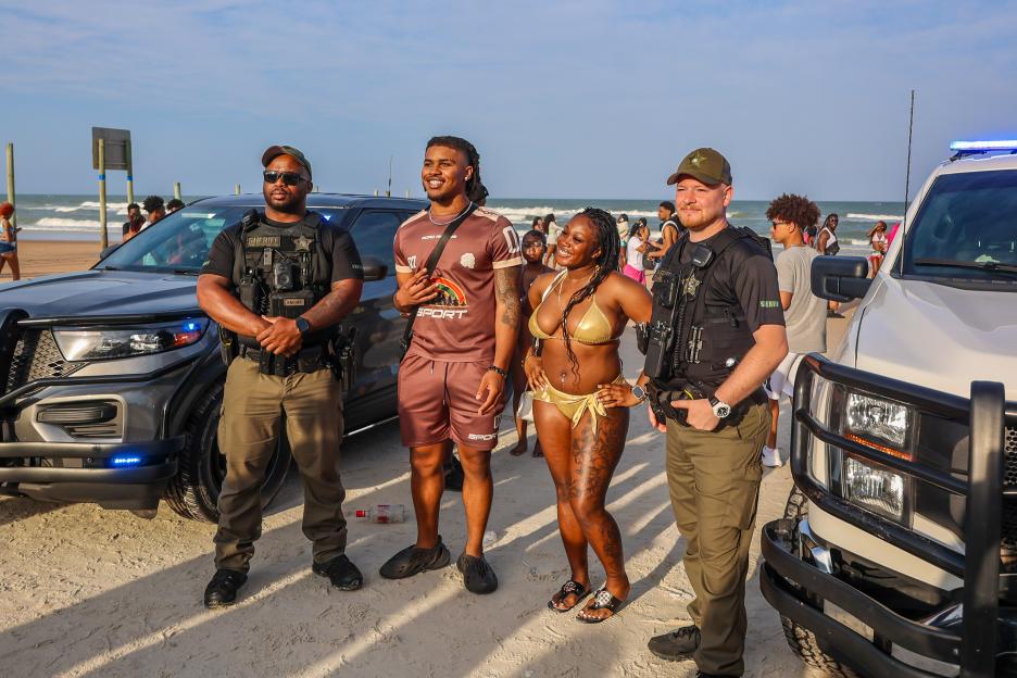 Law enforcement officers and beachgoers at Daytona Beach.