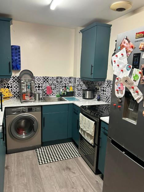 Renovated kitchen with teal cabinets and black and white tile backsplash.