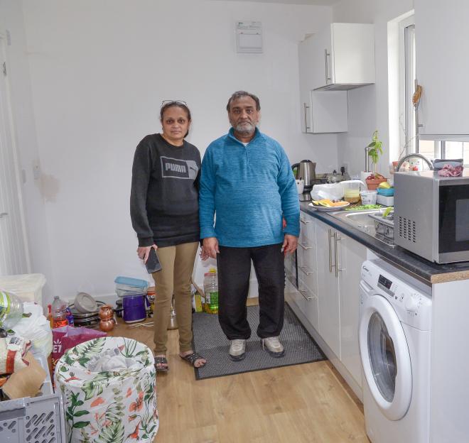 A couple stands in their unfinished kitchen.