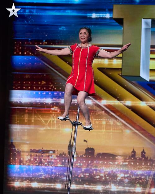 Woman in red dress balancing on a unicycle on Britain's Got Talent.