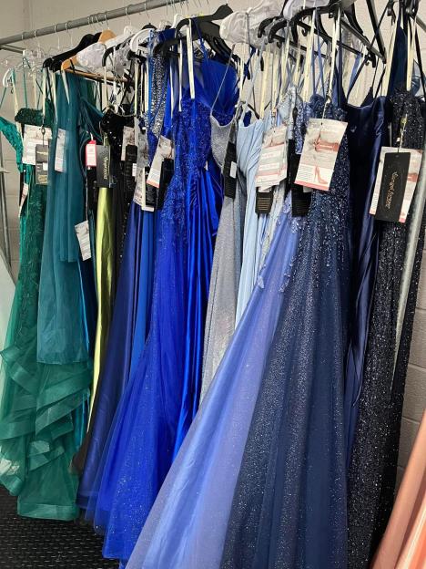 Several formal dresses hanging on a rack.