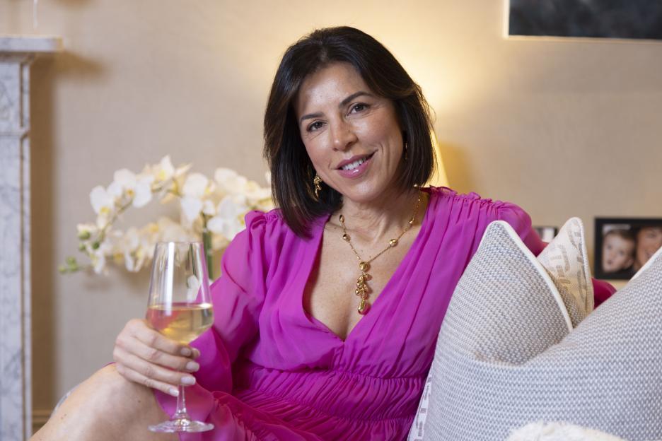 Woman in pink dress holding a glass of wine.