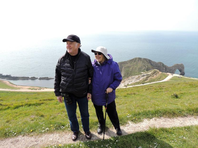 Couple standing on a cliff overlooking the ocean.