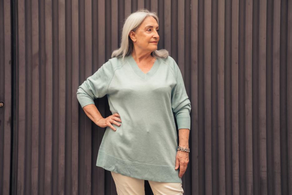 Senior woman standing in front of a slatted wall.