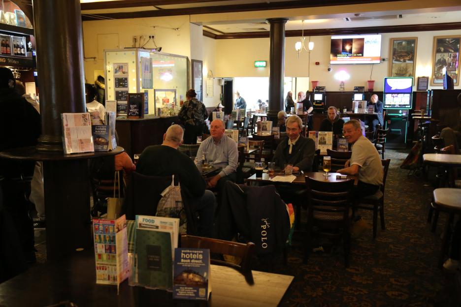 Patrons seated at tables in a Wetherspoon's pub.