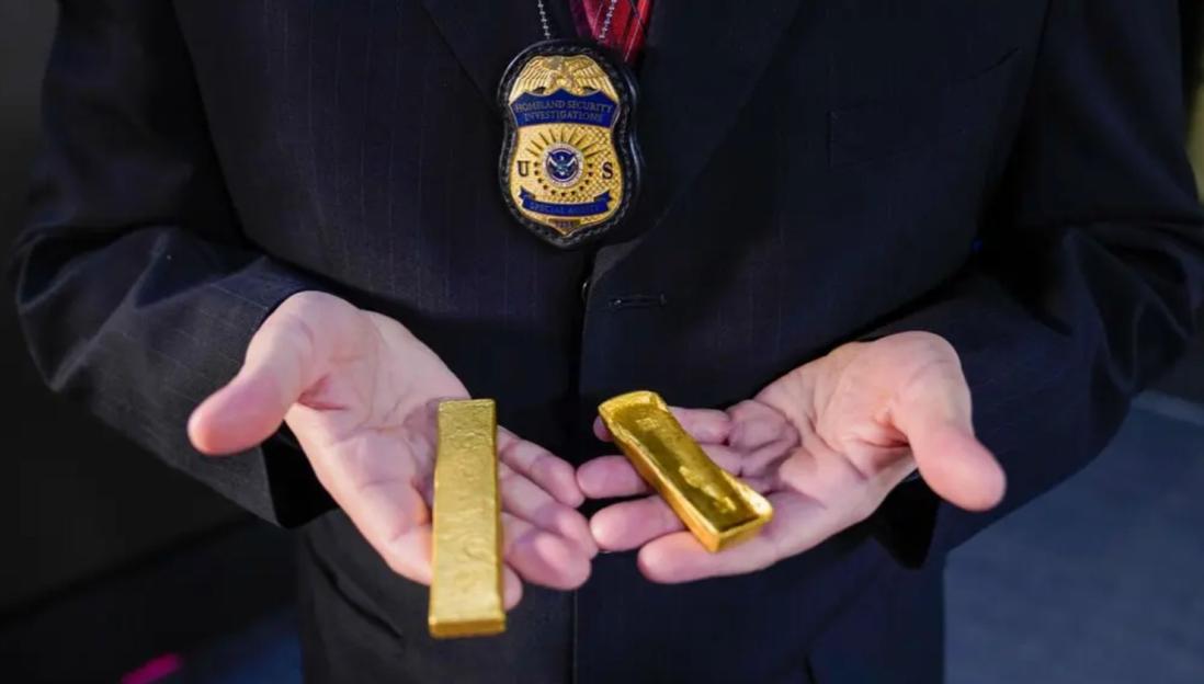 Person in a suit holding two gold bars.