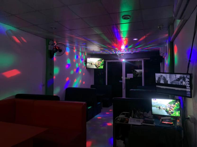 Interior of a karaoke bar at night, illuminated with colorful lights.