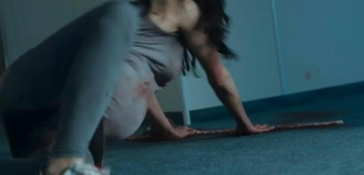 Bloody woman crawling on the floor.