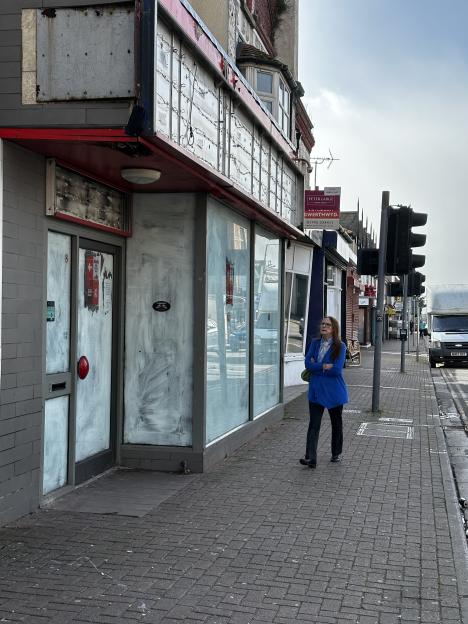 A woman walks past a boarded-up shop in Rhyl.