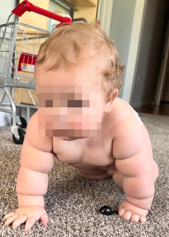 A ten-month-old baby crawling on the floor.