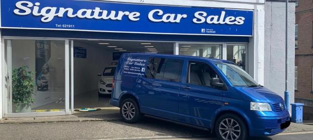 Blue van parked outside Signature Car Sales.